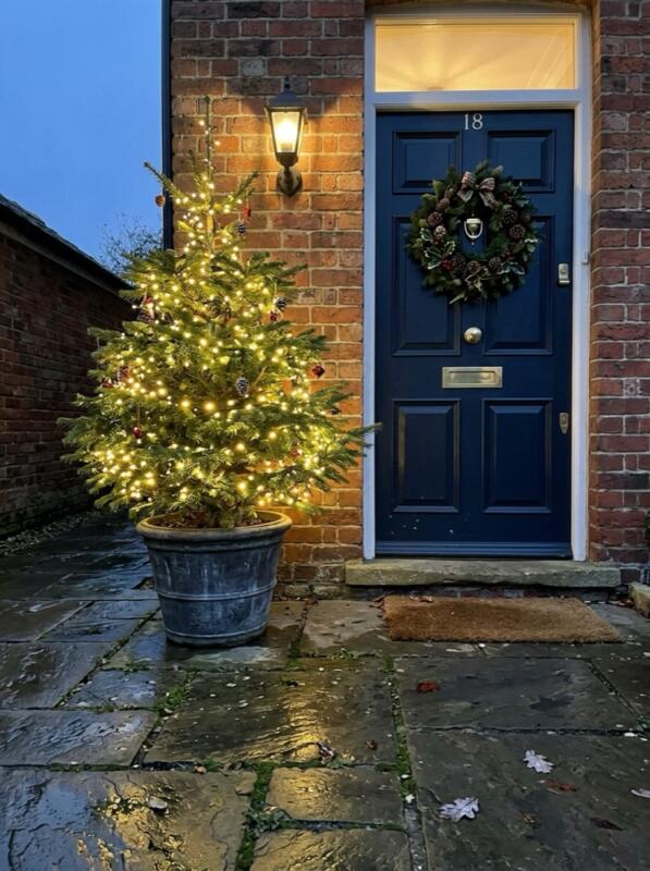 Illuminated Potted Christmas Tree by the Door – Christmas front garden idea for UK homes